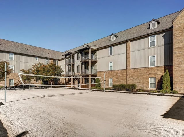 Volleyball court and apartment building exterior at The Lodges of East Lansing in East Lansing Student Accommodation