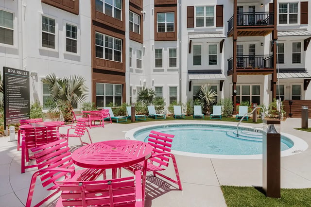 Pink tables chairs pool lounge chairs surrounding pool Pool area at Current Orlando in Orlando Student Accommodation