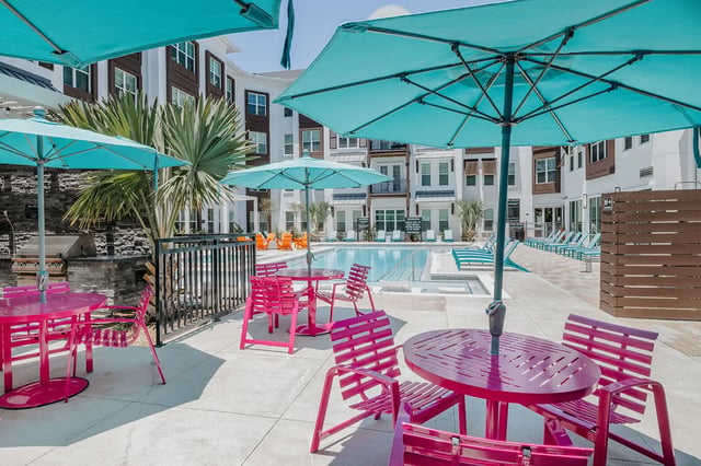 Pink tables umbrellas pool lounge chairs exterior at Current Orlando in Orlando Student Accommodation