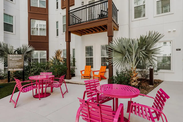 Pink tables chairs orange chairs exterior at Current Orlando in Orlando Student Accommodation