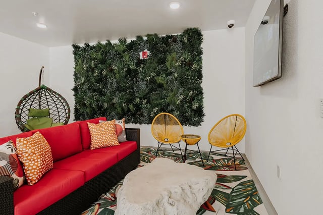 Red sofa hanging chair green wall living room at Current Orlando in Orlando Student Accommodation