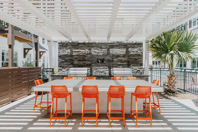 Grill area with concrete counter orange stools outdoor living area at Current Orlando in Orlando Student Accommodation