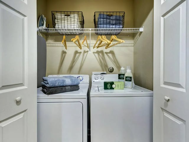 Washer dryer stack towels cleaning supplies laundry room at Villas at Babcock in San Antonio Student Accommodation