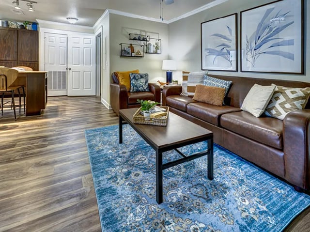 Brown leather sofa armchair coffee table living room at Villas at Babcock in San Antonio Student Accommodation