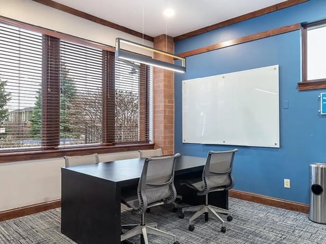 Black table four chairs whiteboard common area at Villas at Chestnut Ridge in Buffalo Student Accommodation