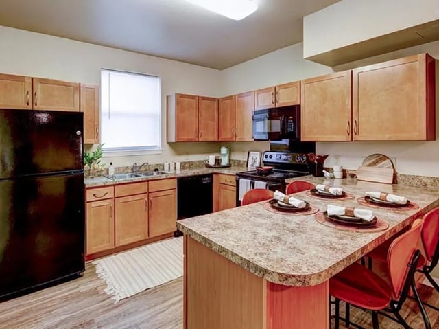 Kitchen with black refrigerator stove and island kitchen at Villas at Chestnut Ridge in Buffalo Student Accommodation