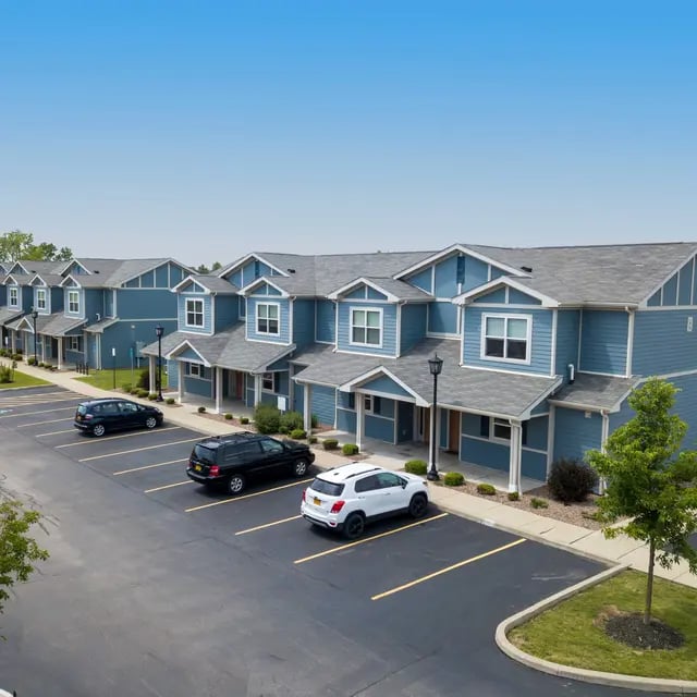 Blue townhouses with cars in parking lot Exterior at Villas on Rensch in Buffalo Student Accommodation