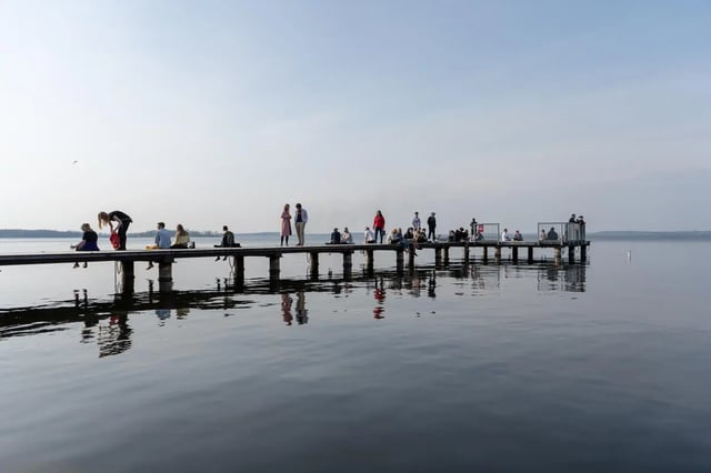 People sitting and standing on pier waterfront exterior at Atmosphere Madison in Madison Student Accommodation