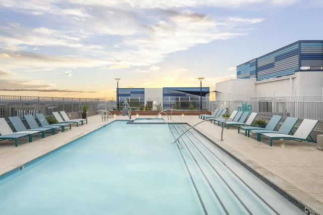 Pool with lounge chairs and modern building exterior at Atmosphere Tempe in Tempe Student Accommodation