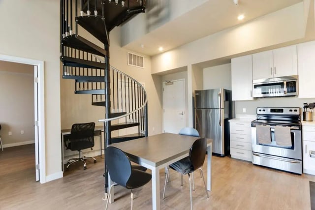 Spiral staircase desk refrigerator stove dining table living room at USC Student Housing: Heritage 1275 in Los Angeles Student Accommodation
