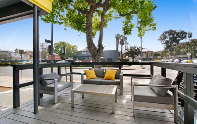 Grey couch table chairs and yellow pillows patio at USC Student Housing: Heritage 2831 in Los Angeles Student Accommodation