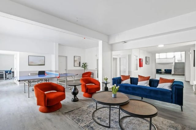 Blue sofa ping pong table orange chairs living room at USC Student Housing: Victory Trio California Suites in Los Angeles Student Accommodation