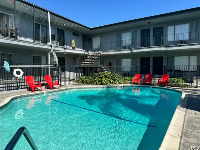 Apartment building with swimming pool and red chairs exterior at USC Student Housing: Victory Trio California Suites in Los Angeles Student Accommodation