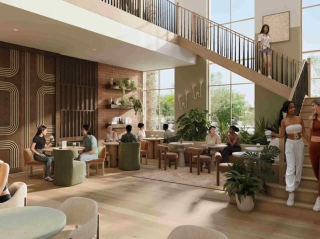 Students gathered at tables with plants and stairs common area at Rambler Tempe Apartments in Tempe Student Accommodation