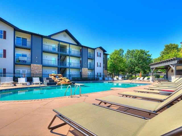 Apartment building pool lounge chairs and waterfall exterior at The Flats at Norman in Norman Student Accommodation