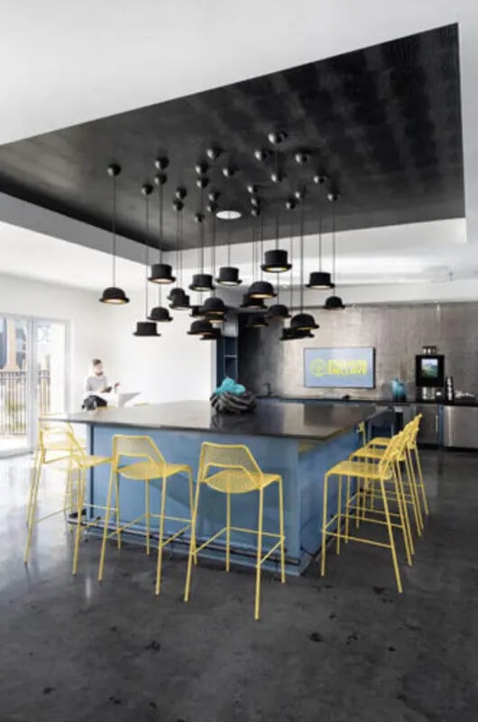 Modern communal area with island and yellow stools kitchen at Stadium Enclave in Tallahassee Student Accommodation