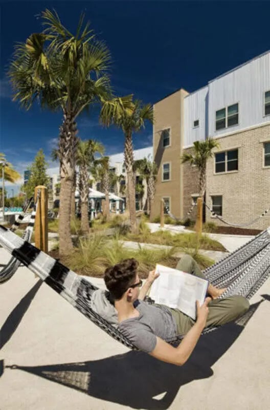 Student reading in hammock outside building exterior at Stadium Enclave in Tallahassee Student Accommodation