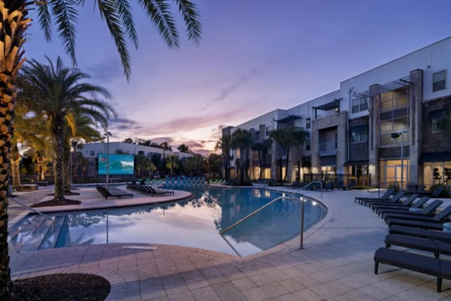 Pool lounge chairs palm trees building exterior at Stadium Enclave in Tallahassee Student Accommodation