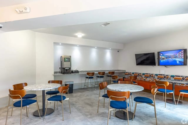 Round tables blue chairs coffee machine lounge area common room at Park East Student Living in Lubbock Student Accommodation