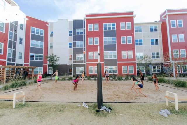 Volleyball players on sand court near apartment buildings Outdoor area at Park East Student Living in Lubbock Student Accommodation