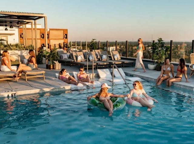 People relaxing at poolside lounge chairs and pool exterior at Sweetwater Gainesville Apartments in Gainesville Student Accommodation