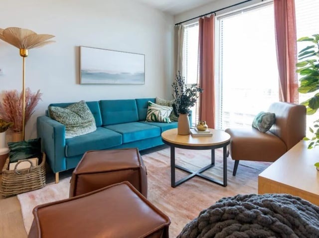 Turquoise sofa leather ottomans coffee table living room at Sweetwater Gainesville Apartments in Gainesville Student Accommodation