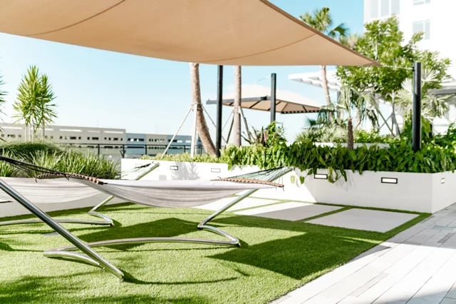 Hammocks on green turf with plants exterior at Lapis in Miami Student Accommodation