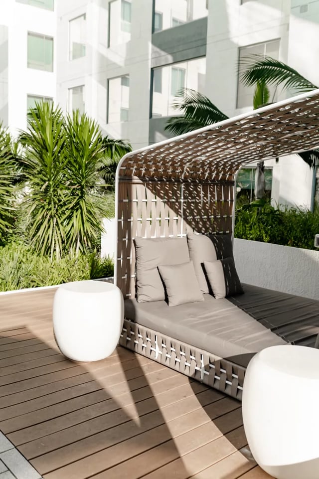Outdoor lounge bed with pillows white tables exterior at Lapis in Miami Student Accommodation