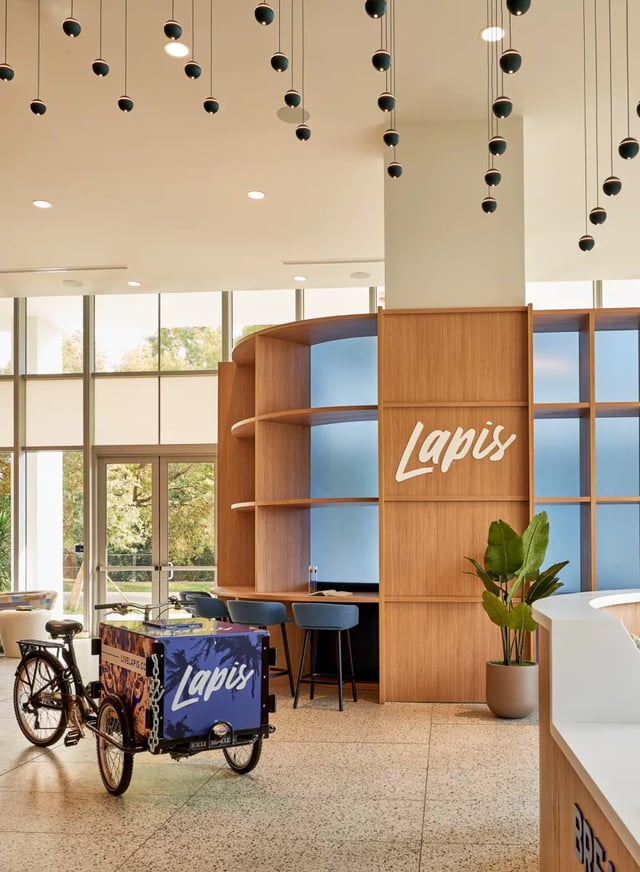 Tricycle cart wooden shelves blue stools reception area at Lapis in Miami Student Accommodation