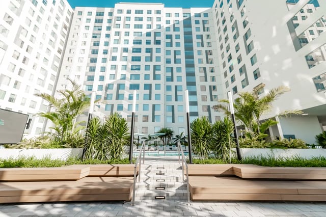 Wooden benches pool and modern building exterior at Lapis in Miami Student Accommodation