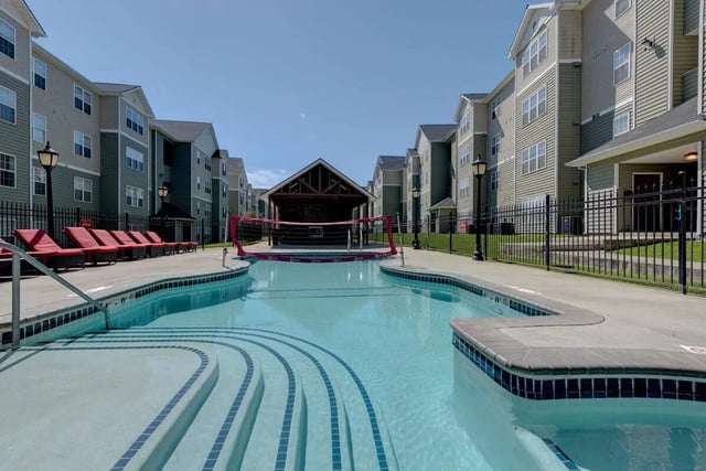 Pool lounge chairs and volleyball net exterior at The Grove Apartments Cheney in Cheney Student Accommodation