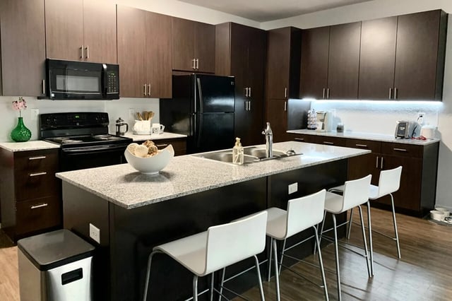 Modern kitchen with island dark cabinets and bar stools kitchen at The Cardinal at West Center in Fayetteville Student Accommodation