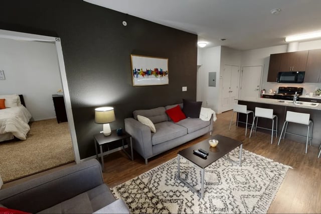 Sofa coffee table rug kitchen island living room at The Cardinal at West Center in Fayetteville Student Accommodation