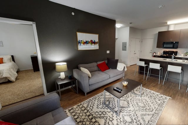 Sofa coffee table kitchen bar stools bedroom living room at The Cardinal at West Center in Fayetteville Student Accommodation