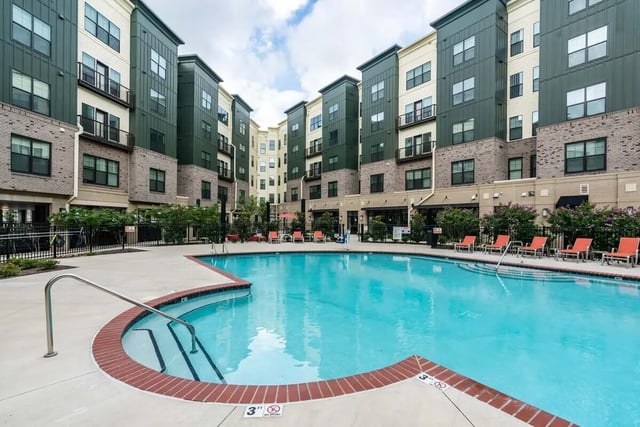 Pool with lounge chairs and apartment buildings exterior at University Edge and Dickinson Lofts in Greenville Student Accommodation