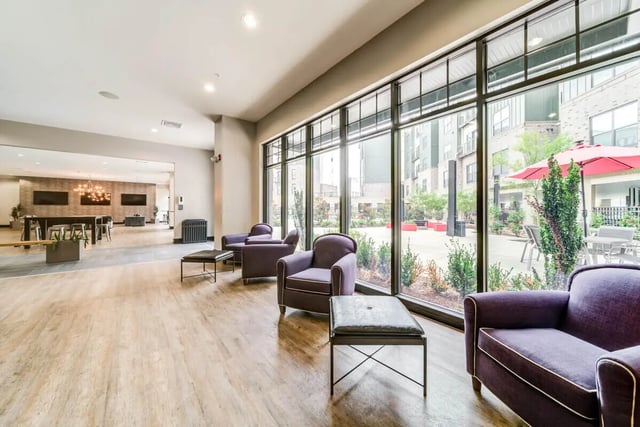 Purple armchairs with tables and courtyard view communal area at University Edge and Dickinson Lofts in Greenville Student Accommodation