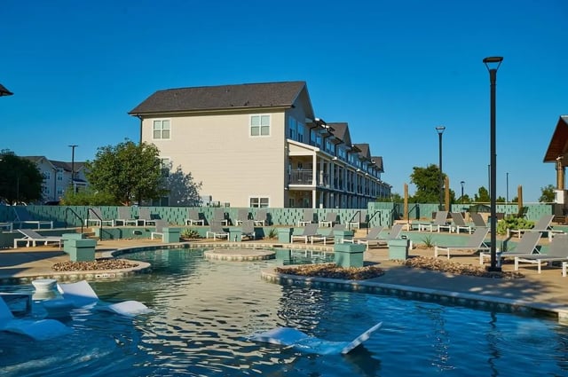 Apartment buildings surrounding a large swimming pool with lounge chairs exterior at Wildwood Lubbock in Lubbock Student Accommodation