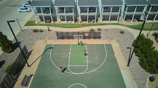 Basketball court with players and apartment buildings exterior at Wildwood Lubbock in Lubbock Student Accommodation