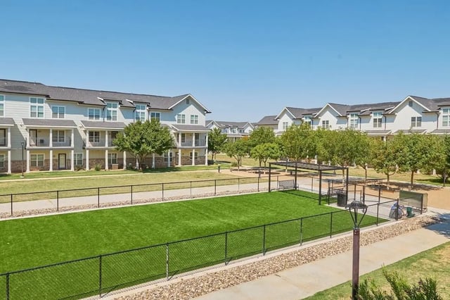 Apartment buildings with balconies and a dog park exterior at Wildwood Lubbock in Lubbock Student Accommodation