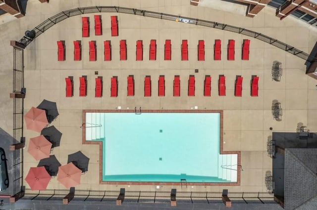 Red lounge chairs pool umbrellas and tables exterior at Registry Apartments in Bowling Green Student Accommodation