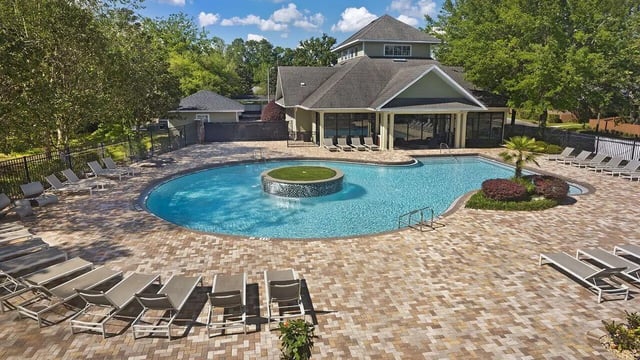 Large swimming pool with lounge chairs and building exterior at Apartments In Gainesville FL in Gainesville Student Accommodation