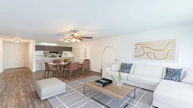 White sectional sofa coffee table rug kitchen living room at Apartments In Gainesville FL in Gainesville Student Accommodation
