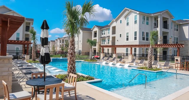 Pool loungers tables umbrellas apartment buildings exterior at The Everson in Cullowhee Student Accommodation