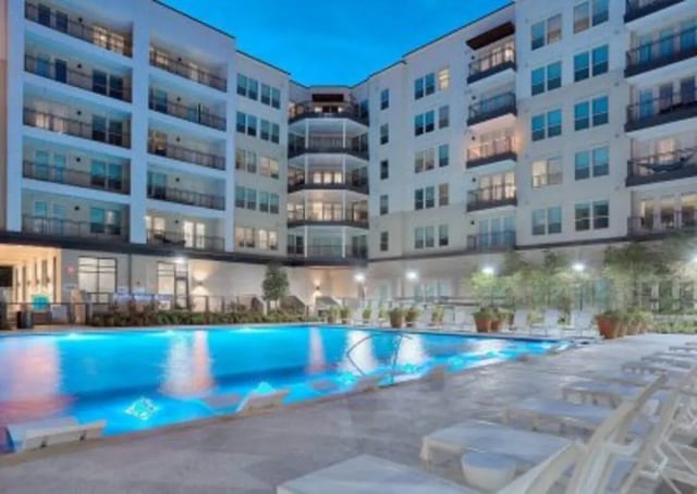 Modern apartment building with illuminated pool and lounge chairs exterior at 101 Center in Arlington Student Accommodation