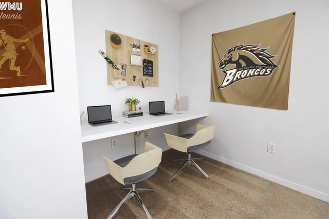 Desk with laptops chairs and Broncos flag study area at The Tate on Howard in Kalamazoo Student Accommodation