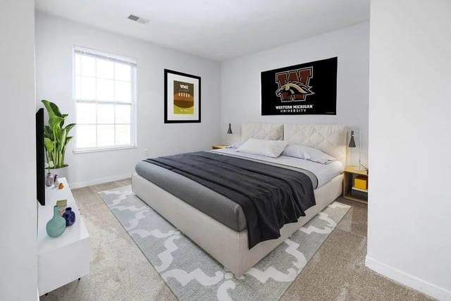 Bed TV plant window Western Michigan banner Bedroom at The Tate on Howard in Kalamazoo Student Accommodation