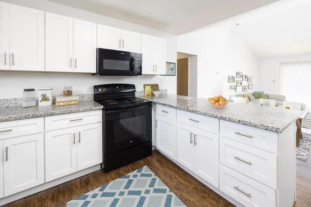 White kitchen cabinets oven microwave granite countertop kitchen at The Tate on Howard in Kalamazoo Student Accommodation