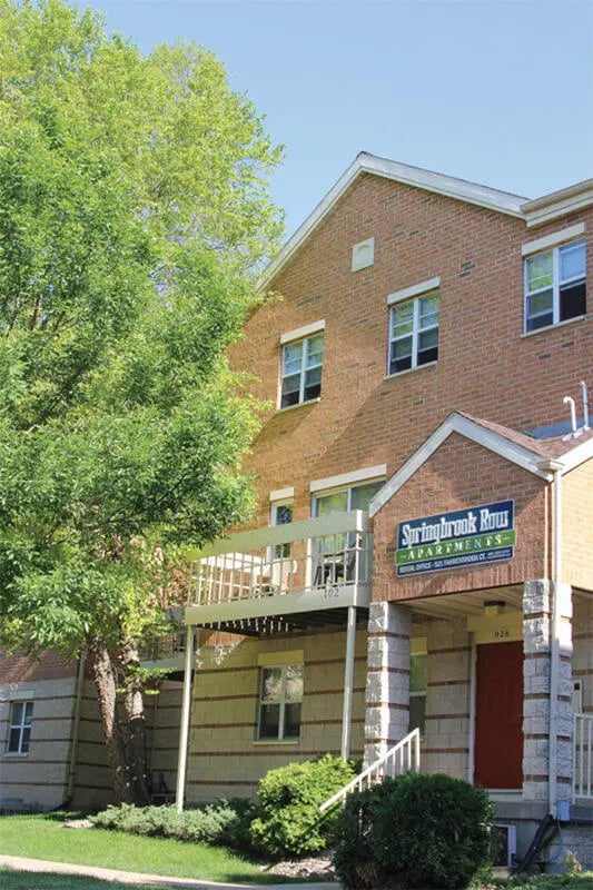 Brick apartment building with balcony and sign exterior at College Park Apartments in Ithaca Student Accommodation