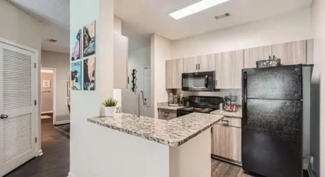 Kitchen with black refrigerator cabinets and granite counters Kitchen at The Flats at Atlantic Station in Atlanta Student Accommodation