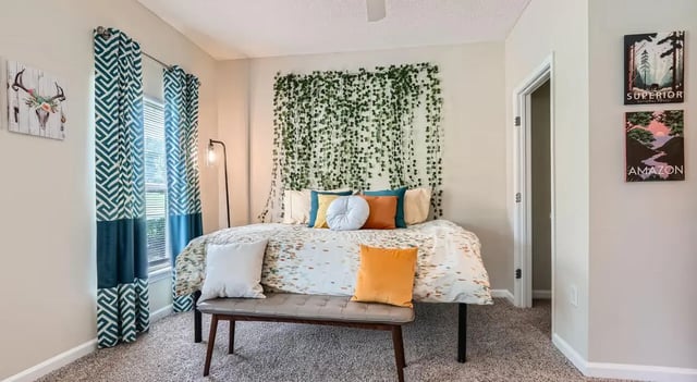 Bed with pillows bench vines and curtains bedroom at The Flats at Atlantic Station in Atlanta Student Accommodation
